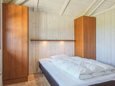 a bedroom with a bed with a wooden wall at Holiday Home Fridgerd - 250m from the sea by Interhome in Blokhus