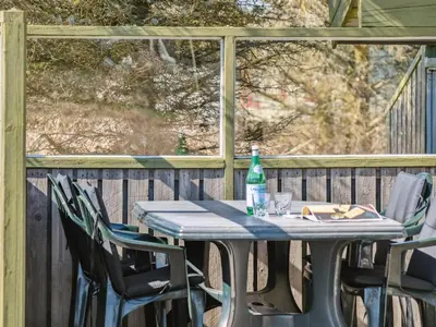 a table with chairs and a bottle on a deck at Holiday Home Tianna - 500m from the sea by Interhome in Pandrup