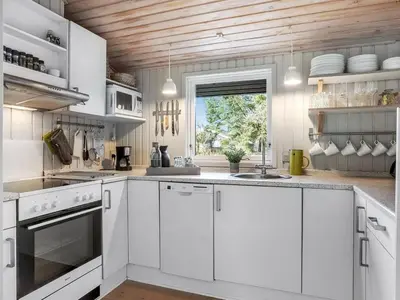 a white kitchen with white cabinets and a window at Holiday Home Apsolon - 600m from the sea by Interhome in Løkken