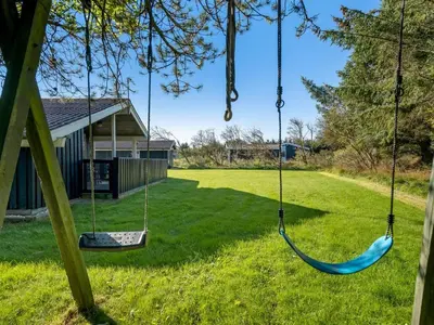 two swings hanging from a tree in a yard at Holiday Home Apsolon - 600m from the sea by Interhome in Løkken