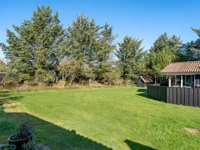 a large lawn with a house in the background at Holiday Home Apsolon - 600m from the sea by Interhome in Løkken