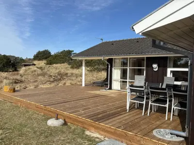 a wooden deck with chairs and a table on a house at Holiday Home Franzisca - 700m from the sea by Interhome in Saltum