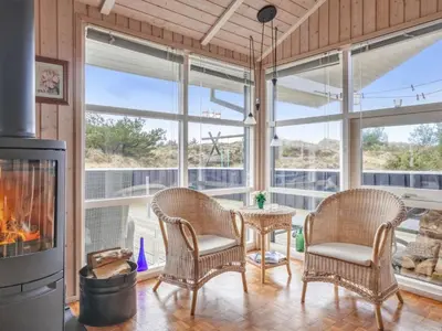 a living room with a table and chairs and a fireplace at Holiday Home Franzisca - 700m from the sea by Interhome in Saltum