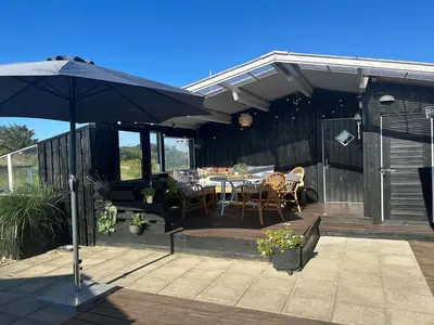 a patio with an umbrella and a table and chairs at Holiday Home Freding - 450m from the sea by Interhome in Løkken