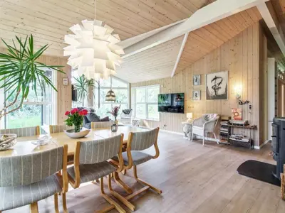 a dining room and living room with a table and chairs at Holiday Home Arlett - 950m from the sea by Interhome in Fjerritslev