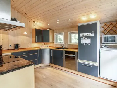 a large kitchen with blue cabinets and a refrigerator at Holiday Home Arlett - 950m from the sea by Interhome in Fjerritslev