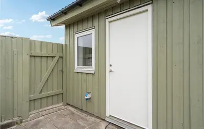 a green building with a white door and a fence at Awesome Home In Løkken in Løkken