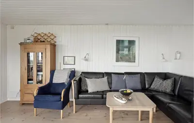 a living room with a black couch and a table at Awesome Home In Løkken in Løkken