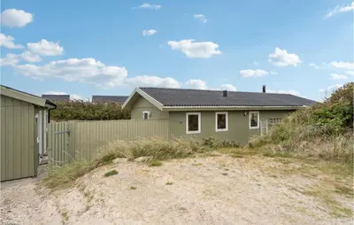 a green house with a fence and a driveway at Awesome Home In Løkken in Løkken