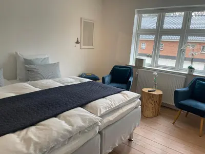 a bedroom with a bed and two blue chairs at Thyholm B&B in Thyholm