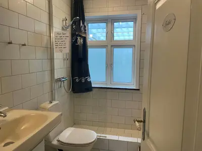 a bathroom with a toilet and a sink and a window at Thyholm B&B in Thyholm