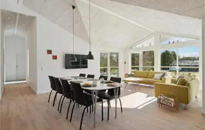 a dining room and living room with a table and chairs at 4 Bedroom Awesome Home In Blokhus in Blokhus