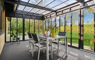 a conservatory with a table and chairs and windows at Awesome Home In Nykøbing M in Hesselbjerg