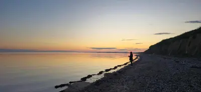 a person standing on a beach holding a fishing pole at Villa Vandkant in Thyholm