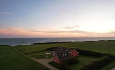 a house in the middle of a field with the ocean at Villa Vandkant in Thyholm