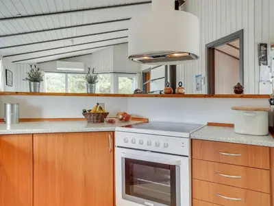 a kitchen with wooden cabinets and a white stove top oven at Holiday Home Floria - 1-4km from the sea by Interhome in Torsted