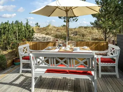 a white table and chairs with an umbrella on a deck at Holiday Home Floria - 1-4km from the sea by Interhome in Torsted