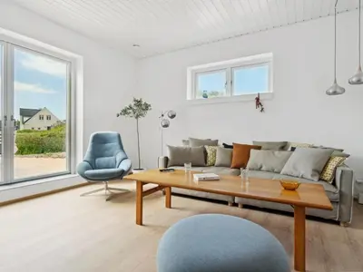 a living room with a couch and a table and a chair at Holiday Home Yakari - 1km from the sea by Interhome in Torsted