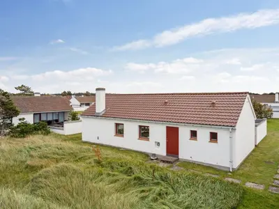 a white house with red doors on a grass field at Holiday Home Werna - 900m from the sea by Interhome in Pandrup