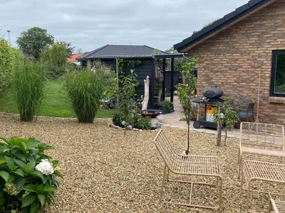 a patio with two chairs and a grill in a yard at Hyggeligt hus. in Holstebro