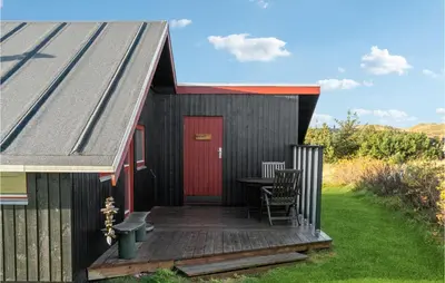 a black house with a red door and a wooden deck at Nice Home In Harboøre With Wifi in Harboør
