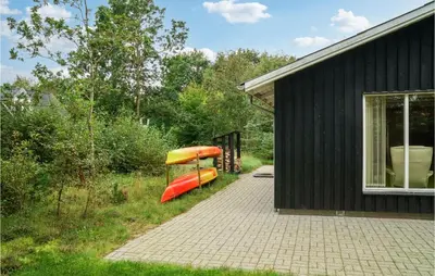 a house with a boat parked next to a building at Nice Home In Thyholm With Wifi in Thyholm