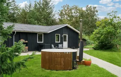 a hot tub in the yard of a black house at Nice Home In Thyholm With Wifi in Thyholm