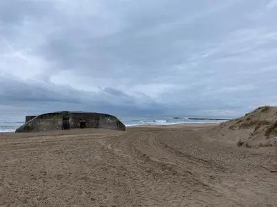 a sandy beach with a building on top of it at Stor lejlighed ved stranden i Agger Cold Hawaii in Agger