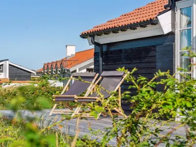 a chair sitting on a deck next to a building at Holiday Home Blaguna - 600m from the sea by Interhome in Torsted