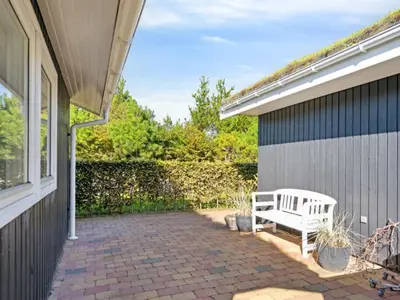 a white bench sitting on a brick patio next to a building at Holiday Home Ofelia - 2-5km from the sea by Interhome in Blokhus