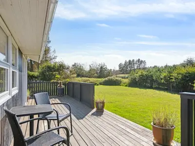 a deck with chairs and tables on a house at Holiday Home Ofelia - 2-5km from the sea by Interhome in Blokhus