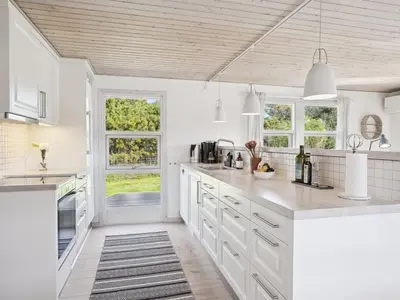 a kitchen with white counters and white cabinets and windows at Holiday Home Ofelia - 2-5km from the sea by Interhome in Blokhus
