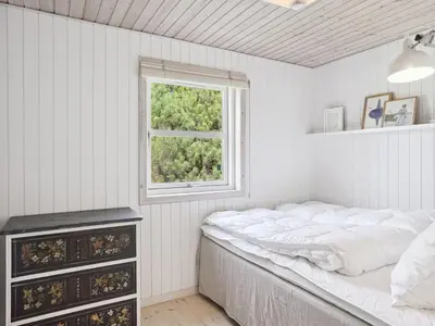 a white bedroom with a bed and a window at Holiday Home Ofelia - 2-5km from the sea by Interhome in Blokhus