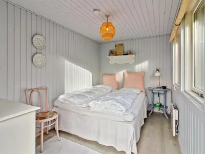 a bedroom with a bed with white sheets and pink pillows at Holiday Home Ofelia - 2-5km from the sea by Interhome in Blokhus