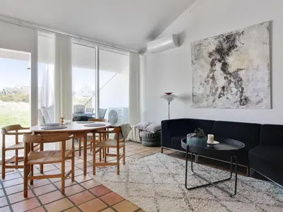 a living room with a couch and a table and chairs at Apartment Virpi - 1km from the sea by Interhome in Blokhus