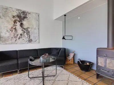 a living room with a black couch and a table at Apartment Virpi - 1km from the sea by Interhome in Blokhus