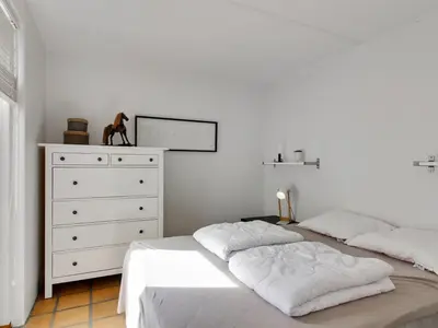 a white bedroom with two beds and a dresser at Apartment Virpi - 1km from the sea by Interhome in Blokhus