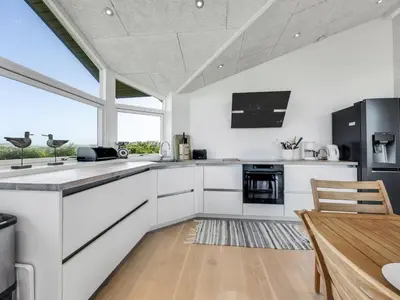 a kitchen with white cabinets and a wooden table at Holiday Home Gebko - 150m from the sea by Interhome in Saltum