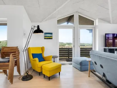 a living room with a yellow chair and a couch at Holiday Home Gebko - 150m from the sea by Interhome in Saltum
