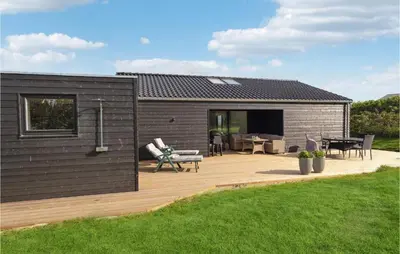 a house with a wooden deck and a patio at Cozy Home In Lemvig With House Sea View in Lemvig