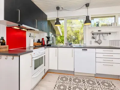 a kitchen with white cabinets and red accents at 6 person holiday home in Nykøbing M-By Traum in Alsted