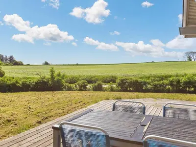 a table and chairs on a deck with a view of a field at 6 person holiday home in Nykøbing M-By Traum in Alsted