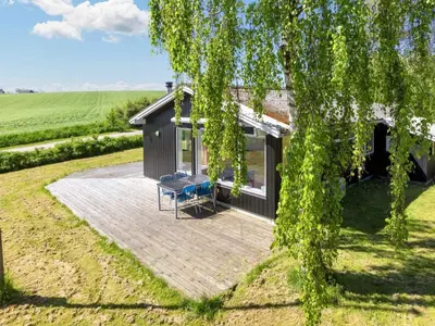 a house with a patio and a tree at 6 person holiday home in Nykøbing M-By Traum in Alsted