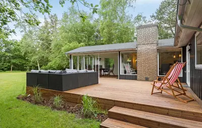 a wooden deck with a chair on a house at 3 Bedroom Nice Home In Thyholm in Thyholm