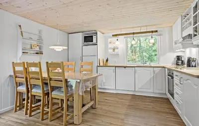 a kitchen with white cabinets and a table and chairs at 3 Bedroom Nice Home In Thyholm in Thyholm