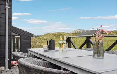 a table with wine bottles and chairs on a balcony at Beautiful Home In Blokhus With Wifi in Blokhus