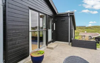 a house with black siding and a patio at Beautiful Home In Blokhus With Wifi in Blokhus