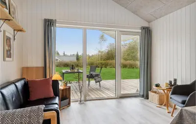 a living room with a sliding glass door with a dog outside at 3 Bedroom Gorgeous Home In Løgstør in Løgsted