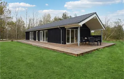 a black house with a wooden deck in a field at 3 Bedroom Gorgeous Home In Løgstør in Løgsted
