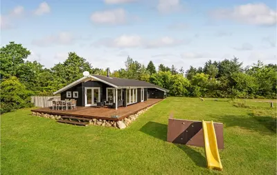 a black cabin with a deck on a grass field at Holiday Home Højslev 42 in Højslev